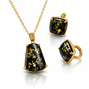 Gold jewelry set featuring a pendant necklace and matching stud earrings with square-cut black onyx stones containing metallic gold flecks, displayed on a reflective white surface.