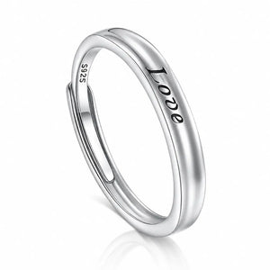 A polished sterling silver ring with the word 'Love' engraved on the outer band and 'S925' stamped on the inner band, shown on a clean white background with a soft reflection.