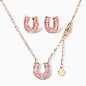 Rose gold horseshoe necklace and earrings set with pink and clear stones on white background
