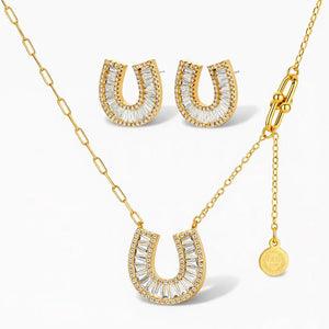 Gold horseshoe necklace and earrings set with clear baguette and pavé crystals on white background