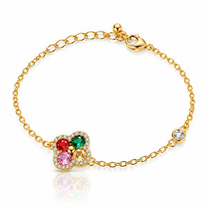 A gold chain bracelet with a central floral charm featuring red, green, and pink stones, surrounded by small clear stones, on a white background.