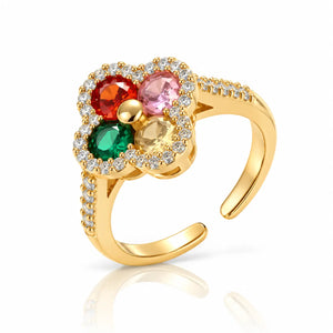 A gold-plated adjustable ring featuring a flower-shaped face with four round gemstones in red, pink, green, and yellow, surrounded by a halo of small clear stones.