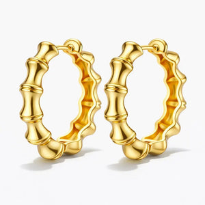 Pair of gold bamboo-style hoop earrings on a white background