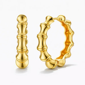 Gold bamboo hoop earrings with textured, sculpted design on white background