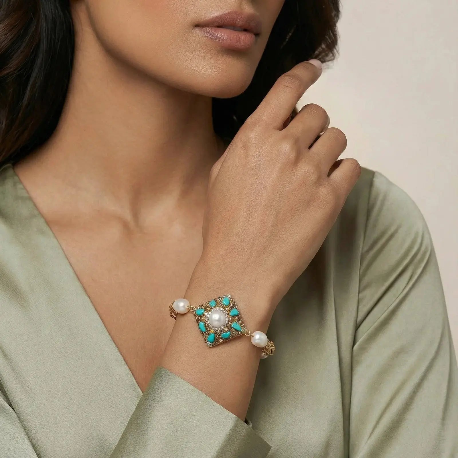 Woman wearing a bracelet with turquoise stones and pearls on a neutral background