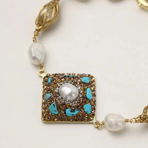 Necklace with gold clasp, pearls, and turquoise stones on a light background