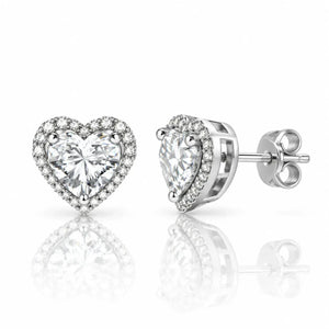 A pair of heart-shaped stud earrings featuring a large clear heart-cut center stone surrounded by a halo of smaller clear stones, shown on a white background with one earring facing forward and the other at an angle showing the post and backing.
