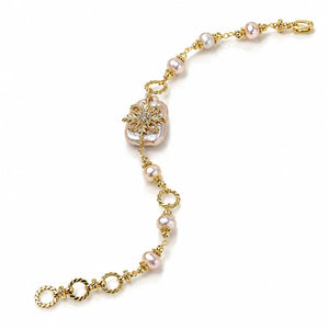 A gold chain bracelet featuring pink freshwater pearls, a central gold floral motif with a clear crystal, and a lobster clasp, shown on a white background.