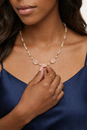 Woman wearing a necklace with pink stones and a blue top.