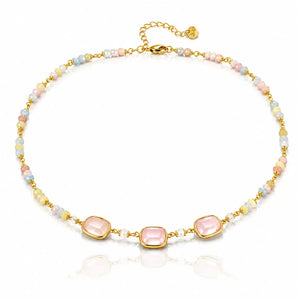 A gold-plated beaded necklace featuring three central light pink cabochon stones, flanked by small pastel beads in pink, blue, yellow, and white, displayed on a clean white background with a soft reflection.