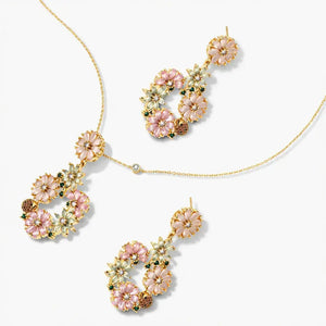 Floral necklace and earring set with pink, gold, and white crystal flowers on gold chains.