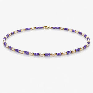 Beaded necklace with purple and gold beads on a white background