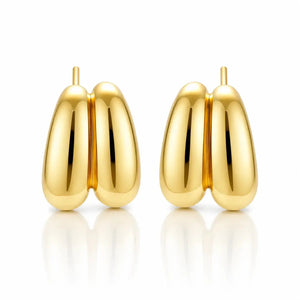 A pair of polished gold hoop earrings with a rounded, organic double-lobed design, displayed on a clean white background with soft reflections below.