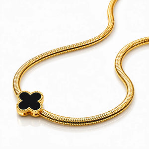 Gold bracelet with a black clover-shaped clasp on a white background
