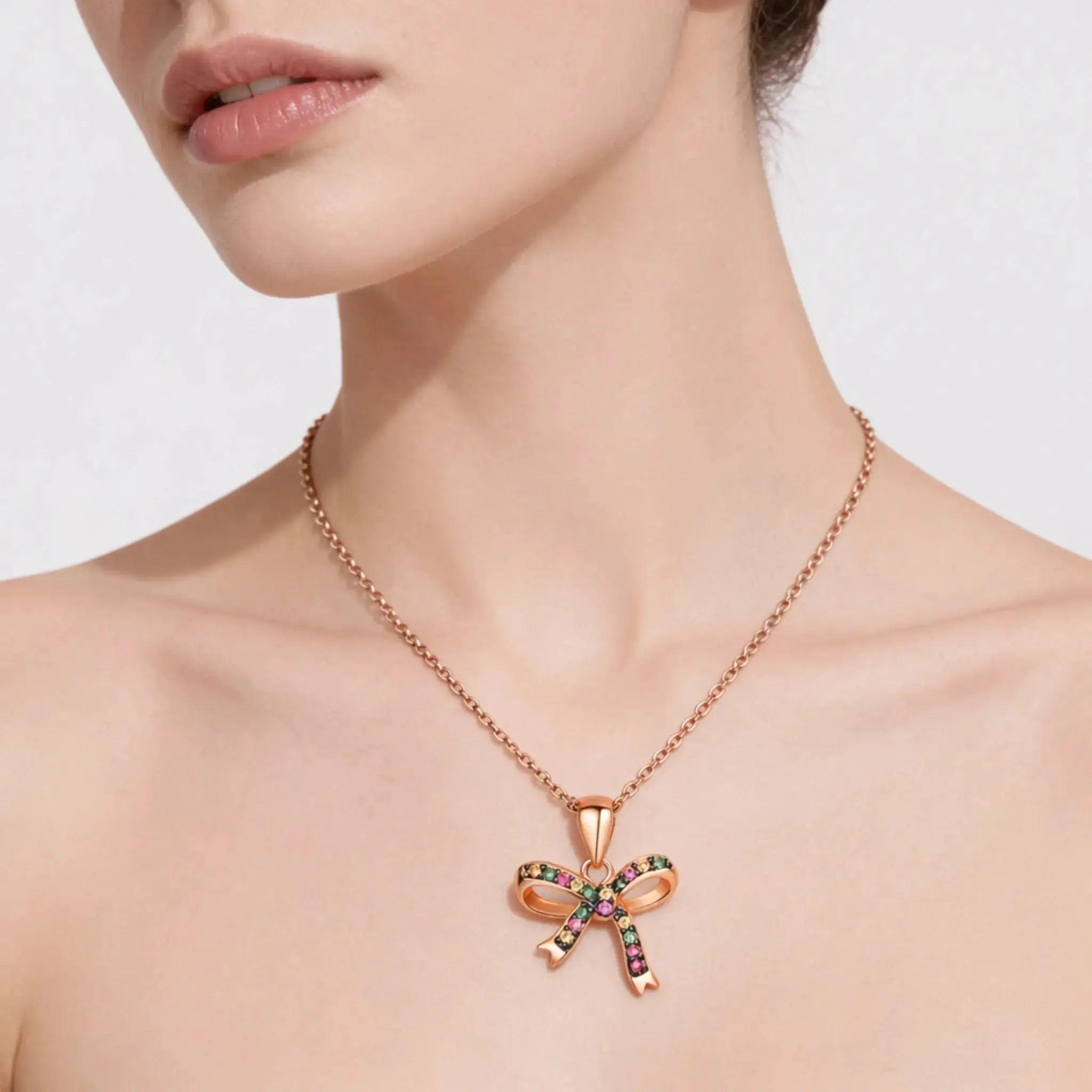 Rose gold bow pendant necklace with colorful gemstones on a woman's neck