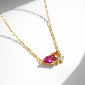Gold necklace with a pink gemstone pendant on a white background