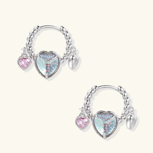 Pair of silver hoop earrings with heart-shaped charms on a white background