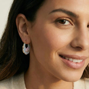 Close-up of a woman wearing a gold earring with a pink gemstone.