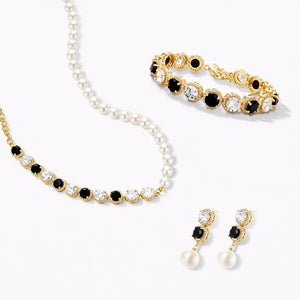 Gold and pearl jewelry set with black and clear stones, including necklace, bracelet, and earrings