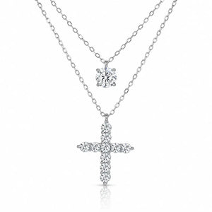 A silver-tone double-strand necklace featuring a small round solitaire pendant and a larger cross pendant paved with small clear stones, shown on a white background.