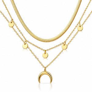 Three layered gold necklaces displayed on a clean white background. The top necklace features a thick textured snake chain, while the two lower necklaces are delicate chain layers adorned with small flat gold discs and a crescent moon pendant at the center.