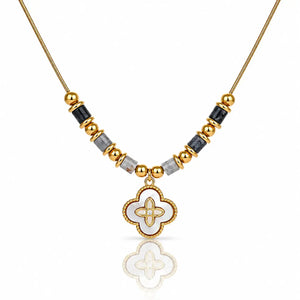 A gold-plated necklace featuring a central white enamel quatrefoil pendant with a gold border, flanked by alternating gold and black faceted beads on a white background.