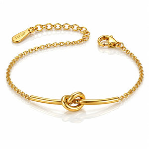 A gold chain bracelet with a central bar and knot design, featuring a lobster clasp and an adjustable chain extender engraved with the brand name 'TOKYO'.
