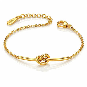 A gold chain bracelet with a central bar and knot design, featuring a lobster clasp and an adjustable chain extender engraved with the brand name 'TOKYO'.