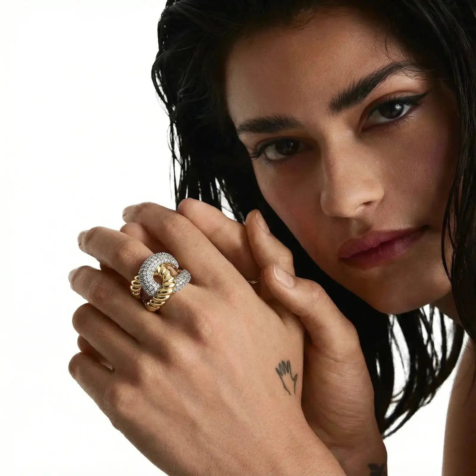 Woman wearing an 18K gold chain ring with pavé crystals on her finger, close-up view