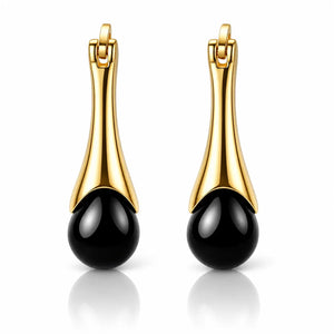 A pair of gold and black drop earrings with a polished gold-tone curved upper section and a glossy black teardrop-shaped bead at the bottom, shown on a white background with a soft reflection.
