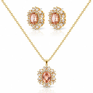 Gold jewelry set featuring a pendant necklace and matching stud earrings with oval peach-pink center stones surrounded by clear crystals on a white background.