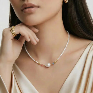 Woman wearing a pearl and emerald beaded necklace with gold vermeil details