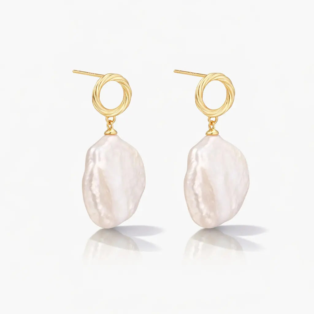 Pair of gold vermeil earrings with large baroque freshwater pearl drops on white background.