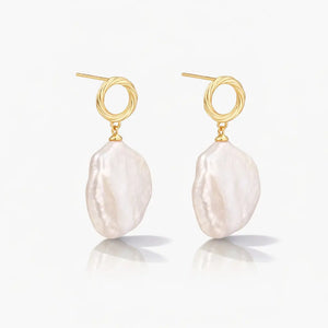 Pair of gold vermeil earrings with large baroque freshwater pearl drops on white background.