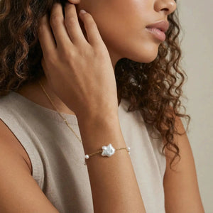 Woman wearing a gold chain bracelet with baroque pearl centerpiece and accent pearls