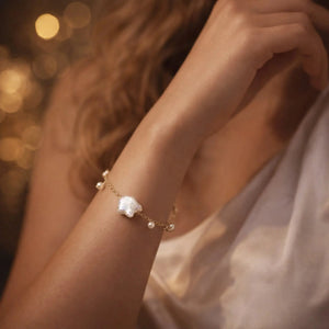 Gold chain bracelet with baroque and round pearls on woman's wrist, elegant evening setting