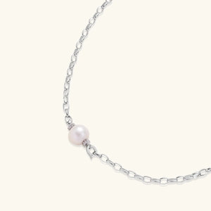 Silver chain necklace with a single pearl on a white background