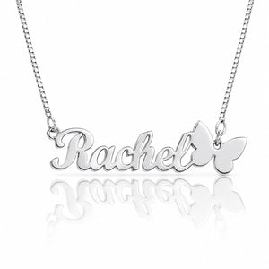 A silver nameplate necklace spelling 'Rachel' in cursive, with a butterfly pendant on the right side, suspended from a silver chain against a white background with a soft reflection below.