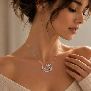 A close-up lifestyle shot of a woman wearing a silver necklace with a custom nameplate in the shape of Hello Kitty. The nameplate is personalized with the name 'Emily' in cursive script.