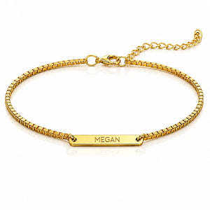 A gold-plated chain bracelet with a rectangular nameplate engraved with the name 'MEGAN', displayed on a clean white background.