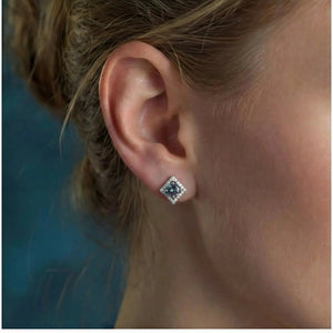 Square silver stud earring with rainbow moissanite and halo diamonds on ear