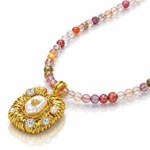 A luxury gold necklace featuring a textured gold pendant with a central white pearl and clear crystals, connected to a strand of faceted multicolor beads on a white background.
