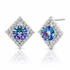 A pair of diamond-shaped stud earrings featuring iridescent blue and purple center stones surrounded by a halo of small clear stones, set in silver-toned metal on a white background with a soft reflection.