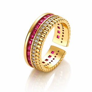 A gold-plated open cuff ring featuring a channel-set row of bright pink gemstones and a row of small clear stones, shown on a reflective white background.