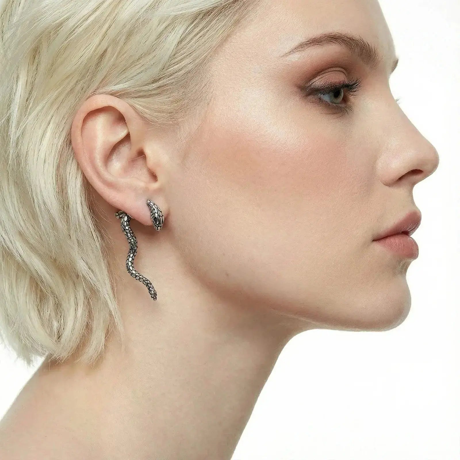 Woman wearing white gold snake drop earrings with serpent design