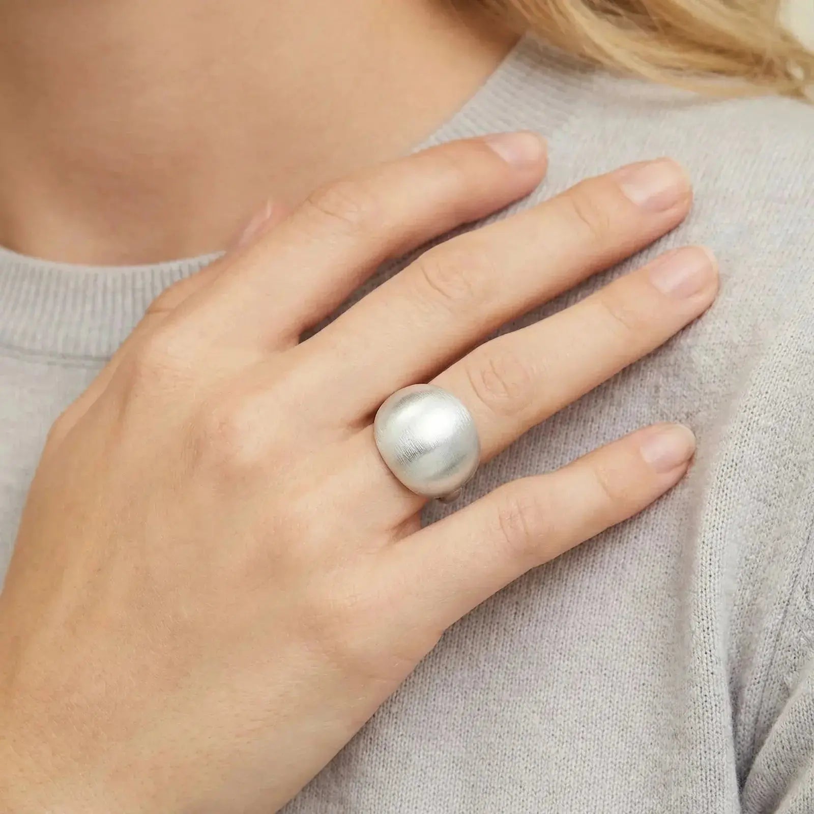 Hand wearing a bold dome-shaped 925 silver ring on index finger, light sweater background
