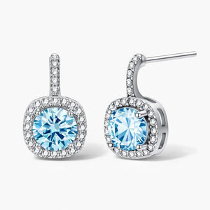 Silver stud earrings with round blue gemstones and sparkling halo accents on a white background