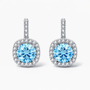 Elegant silver drop earrings with round blue gemstones and pavé clear stones on a white background