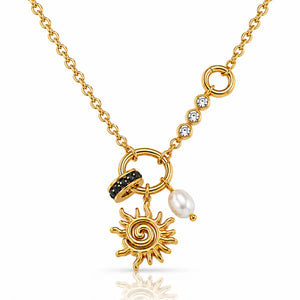 A gold chain necklace featuring a sunburst charm, a black stone-accented ring, a white pearl bead, and a line of clear cubic zirconia stones on a white background.