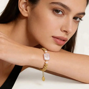 Woman wearing an 18K gold-plated bracelet with baroque pearl and rope chain details